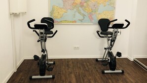Duas bicicletas ergométricas numa sala com um grande mapa-múndi na parede.