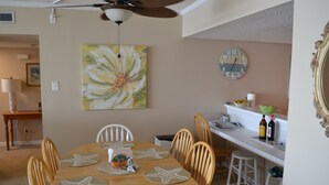 A dining area with a round table set with starfish placemats, wooden chairs, and a ceiling fan. - Beach Front 2 bedroom 2 bath 7th floor condo in the prestigious Brigadune  (Myrtle Beach)