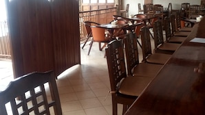A restaurant with wooden furniture, a long counter, and a television screen on the wall. - Countryhouse Inn Hotel (Naivasha)
