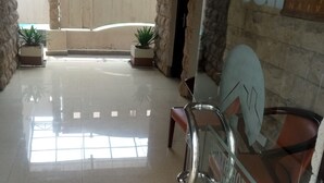 A lobby with a reception desk, a glass partition, and a sign indicating a poolside dining area. - Countryhouse Inn Hotel (Naivasha)