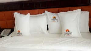 A hotel room with a bed, white pillows, a phone, and a headboard. - Countryhouse Inn Hotel (Naivasha)