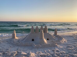 A sandcastle on a beach with the ocean in the background.