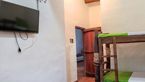 Ein Stockbett mit an der Wand montiertem Fernseher, eine Holzleiter und eine Tür zu einem anderen Raum.
