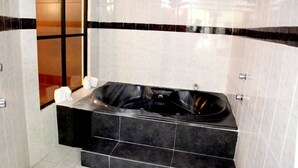 A modern bathroom with a black and white tiled wall, a glass shower enclosure, and a black bathtub. - Hotel Cuandón (Tepeji del Río de Ocampo)