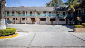 A multi-story hotel with a parking area, a covered walkway, and a palm tree. - Hotel Cuandón (Tepeji del Río de Ocampo)