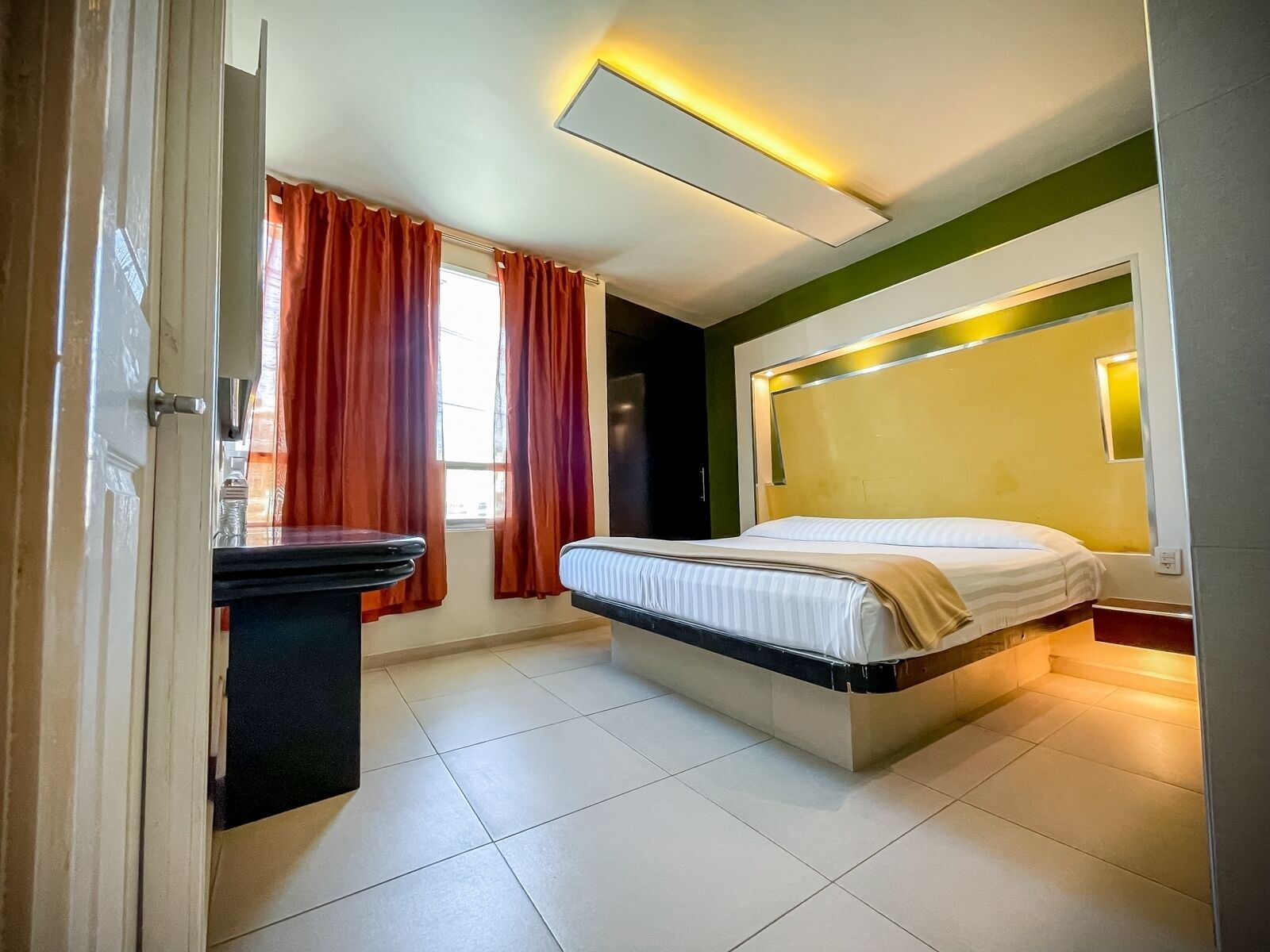 Una habitación de hotel moderna con cama, escritorio y ventana con cortinas.