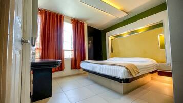 Una habitación de hotel moderna con cama, escritorio y ventana con cortinas.