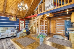 A log cabin interior with a dining area, a staircase, and a kitchen.