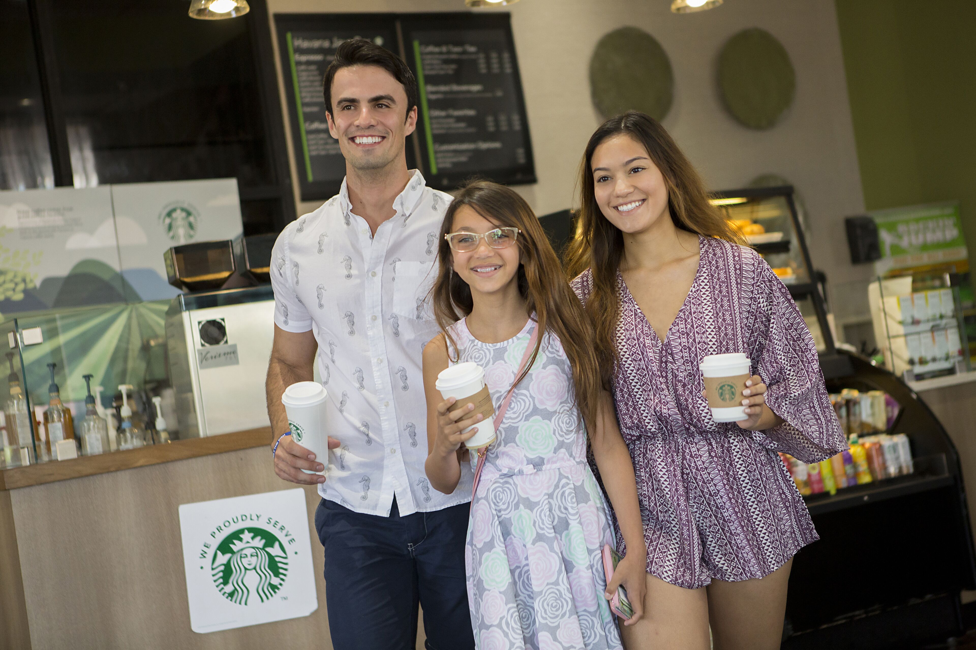 Intérieur d’un café Starbucks, avec un panneau affichant le menu, des machines à café et un comptoir orné du logo Starbucks.