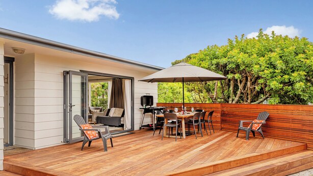 Une terrasse extérieure couverte, équipée d’une table à manger, de chaises et d’un parasol.