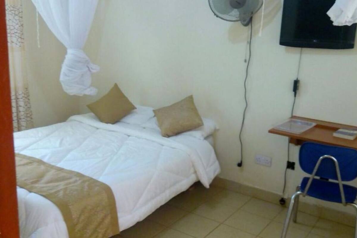 Una habitación pequeña y limpia con una cama, un escritorio y una silla.