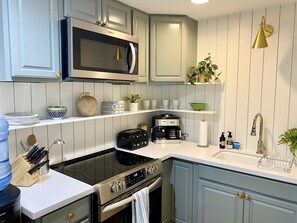 Eine moderne Küche mit integriertem Mikrowellenherd, Herd und Backofen, sowie einer Kaffeemaschine und verschiedenen Küchenutensilien.