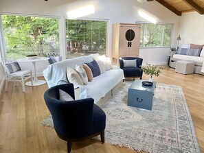 Ein modernes Wohnzimmer mit Sofa, Sesseln, Couchtisch und einem Essbereich mit Tisch und Stühlen.