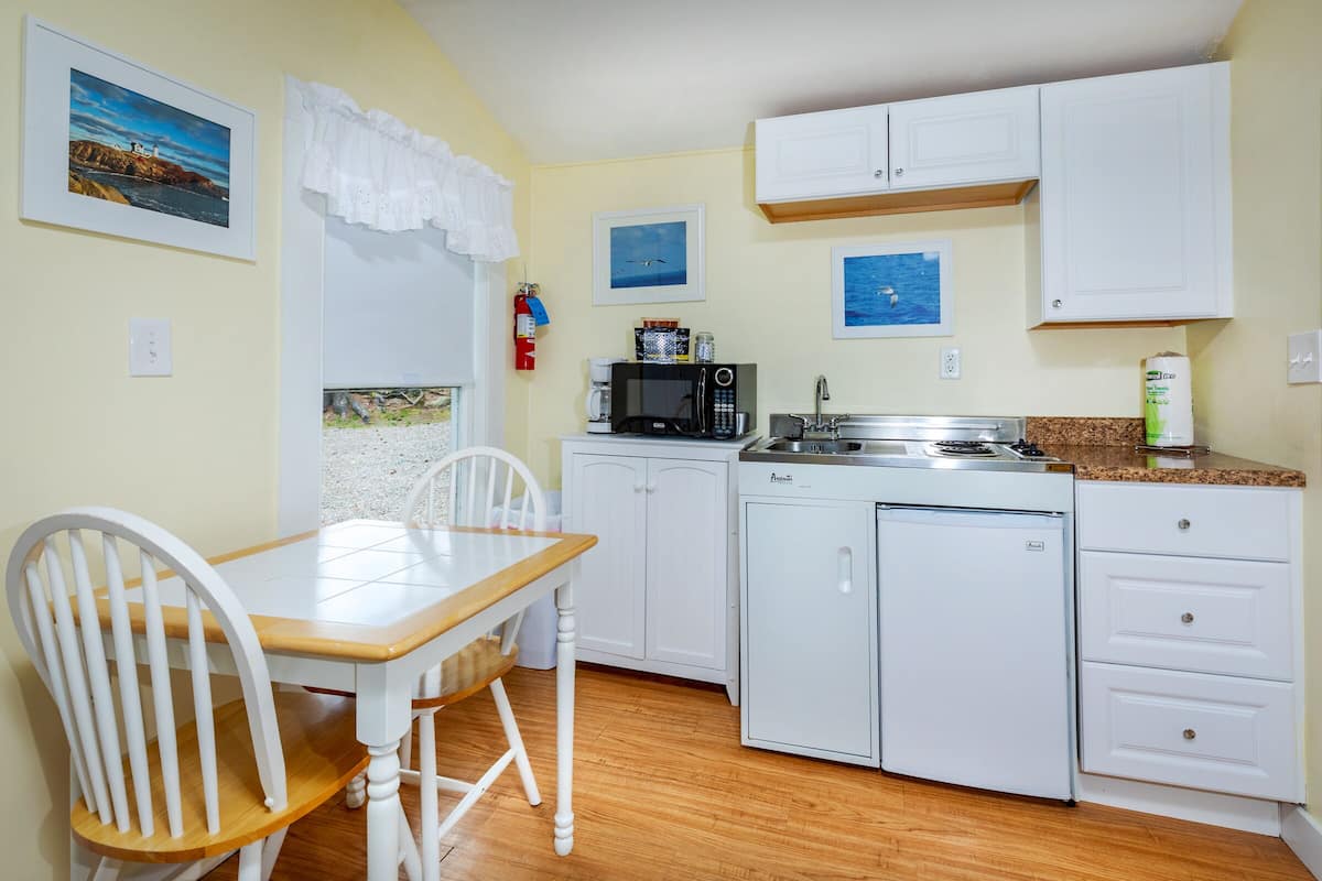 A compact kitchen with white cabinets, a wooden dining table, and chairs.