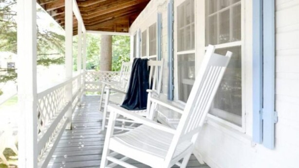 A covered porch with white wooden chairs and a blue cloth draped over one. - 2 River Road Inn and Cottages (Cape Neddick)
