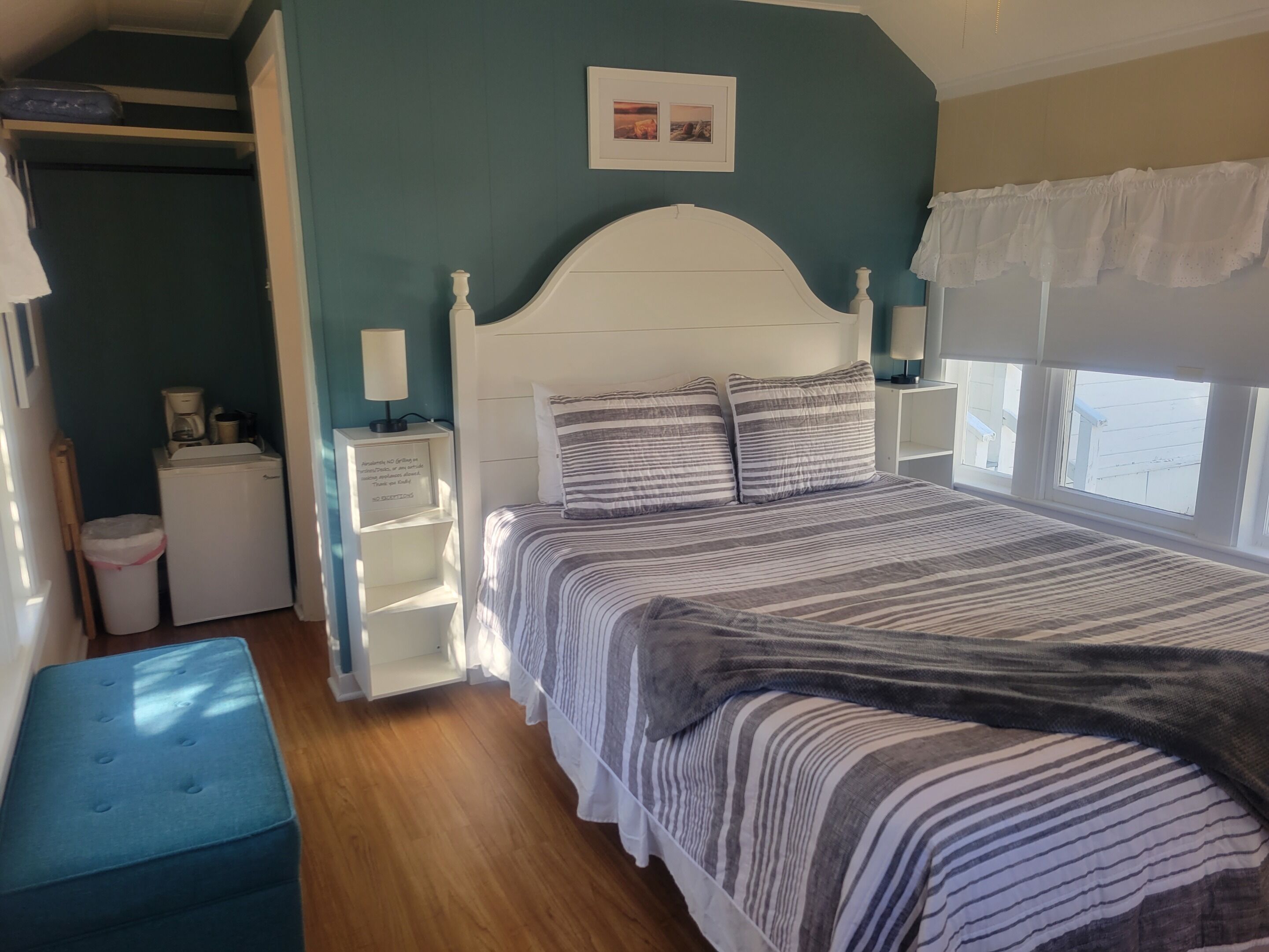 Une chambre à coucher comprenant un lit, des tables de chevet, un banc, une armoire et une fenêtre.