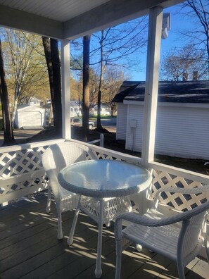 A covered porch with a round glass table and white wicker chairs. - 2 River Road Inn and Cottages (Cape Neddick)