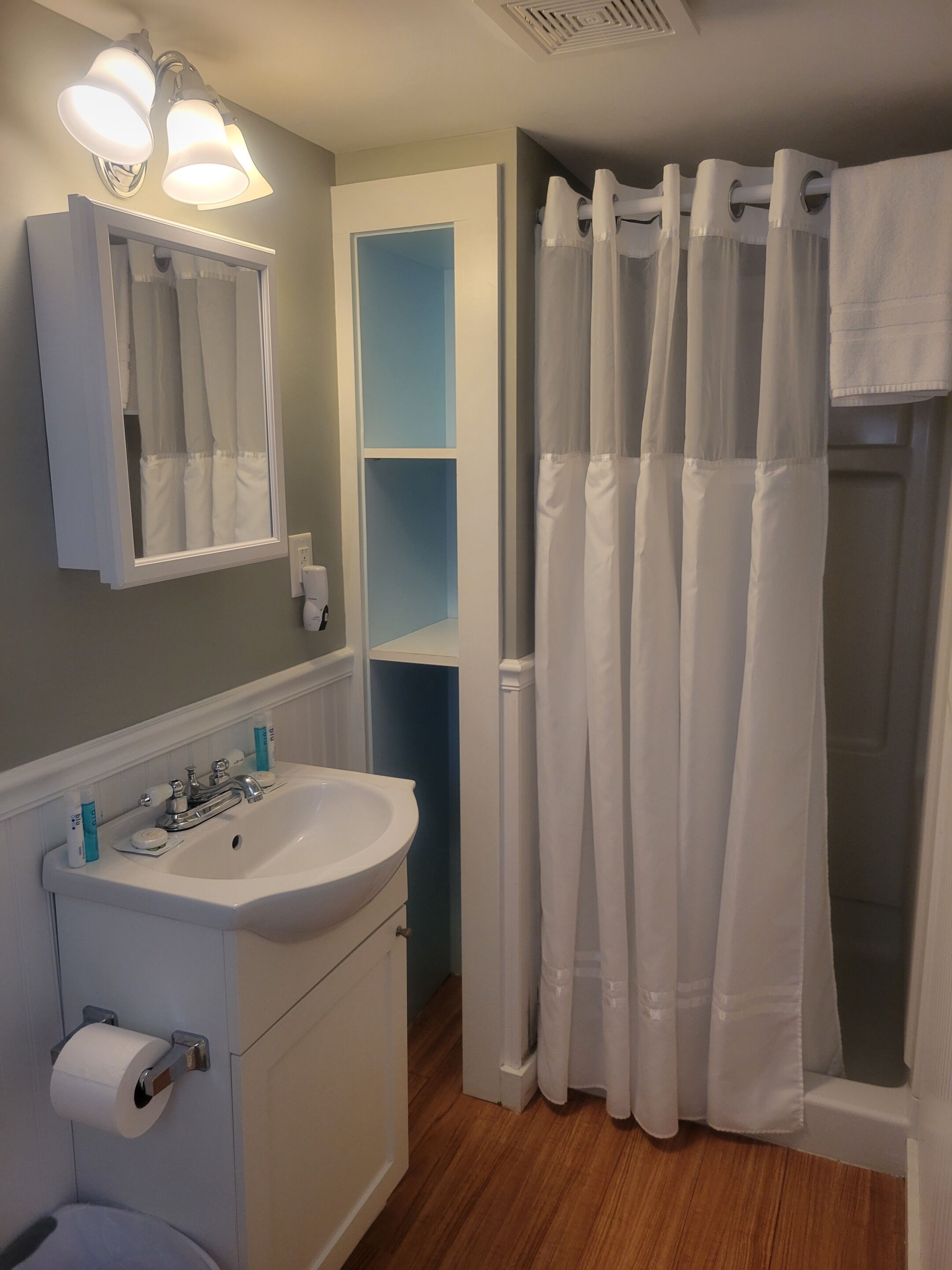 A bathroom with a white sink, mirror, and shower curtain.