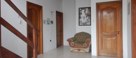 Un pasillo con una escalera de madera, una silla y una puerta.