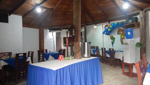A dining area with a blue tablecloth, wooden chairs, and a high ceiling with exposed beams. - Hotel La Gran Tortuga (Puerto Villamil)
