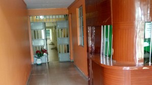 A corridor with a reception desk, tiled floor, and a door leading to another room. - Epco Guest House (Naivasha)