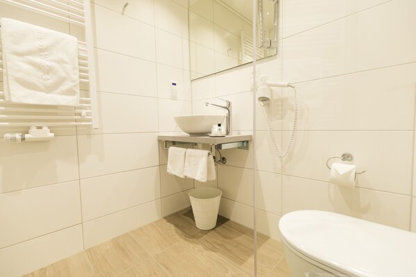 A modern bathroom with a white sink, mirror, and toilet.