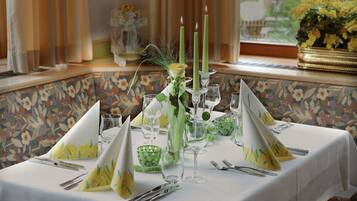 Une table dressée avec des serviettes vertes et jaunes, de la vaisselle transparente et des bougies.
