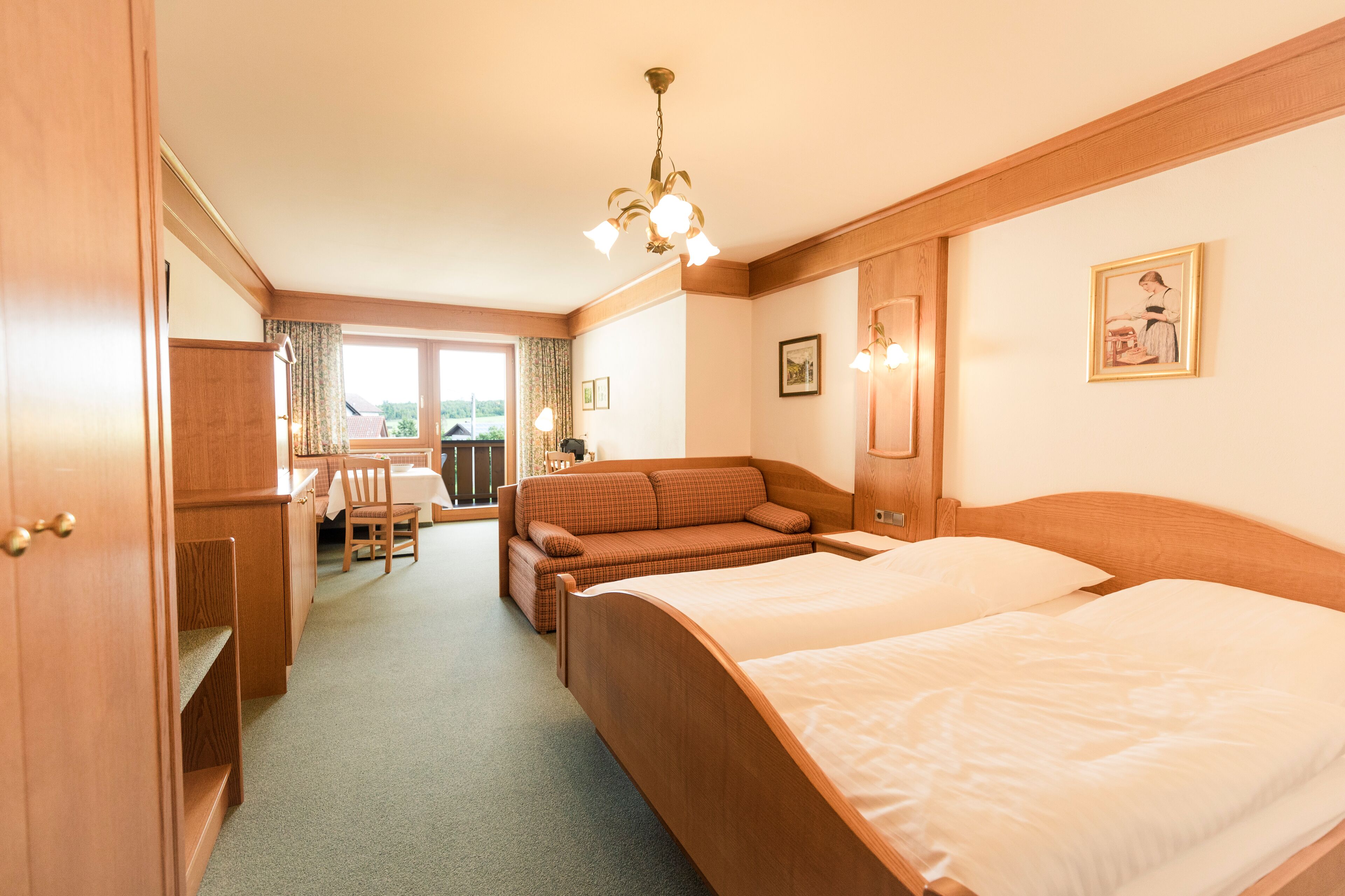 A hotel room with a large bed, a sofa, a desk, and a dining area with a view.