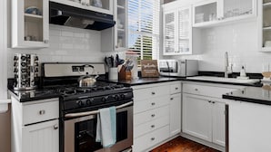 Una cocina con muebles blancos, una estufa y un lavaplatos.