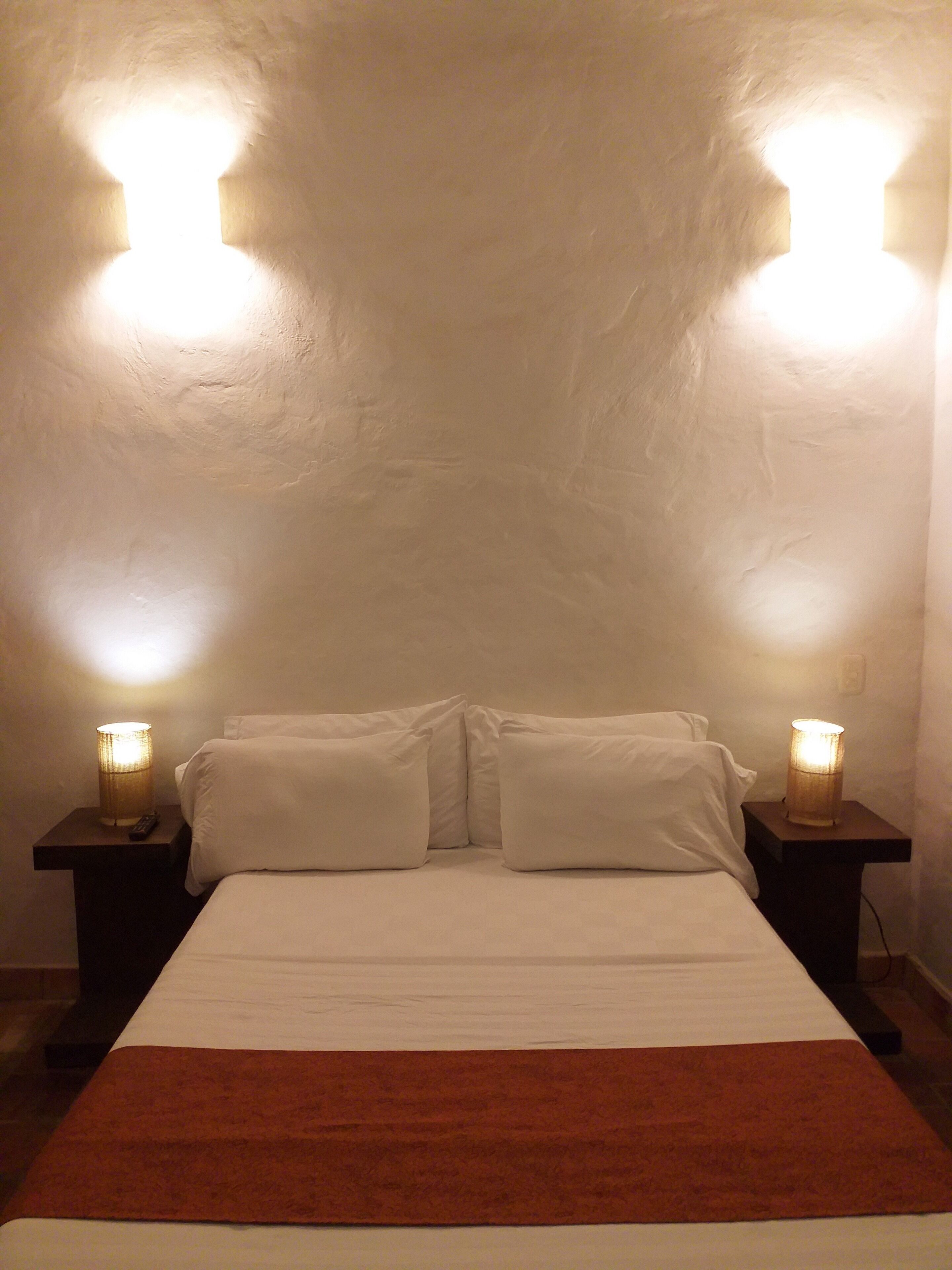 A bedroom with a bed, two bedside lamps, and a nightstand.