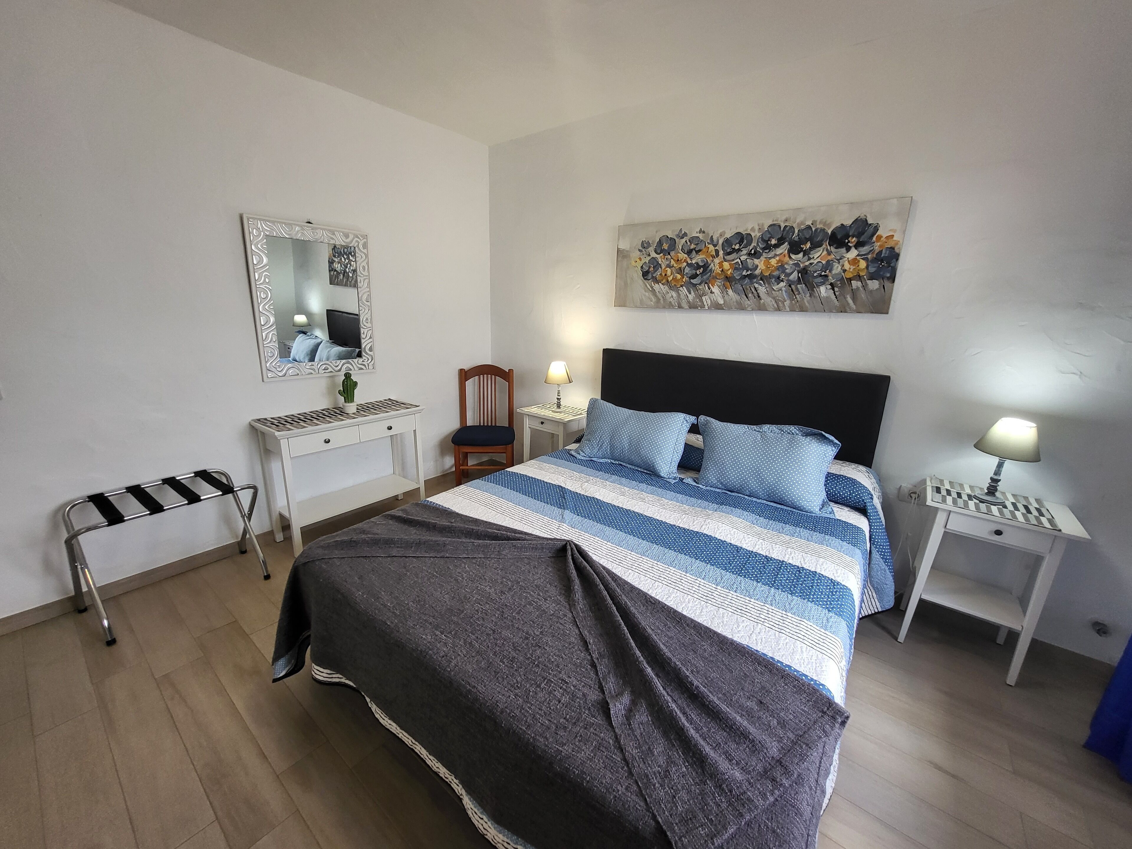A bedroom with a bed, bedside tables, a desk, a chair, and a mirror.