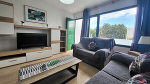 Una sala de estar moderna con un televisor de pantalla plana, una mesa de centro de madera, un sofá gris y una puerta verde.