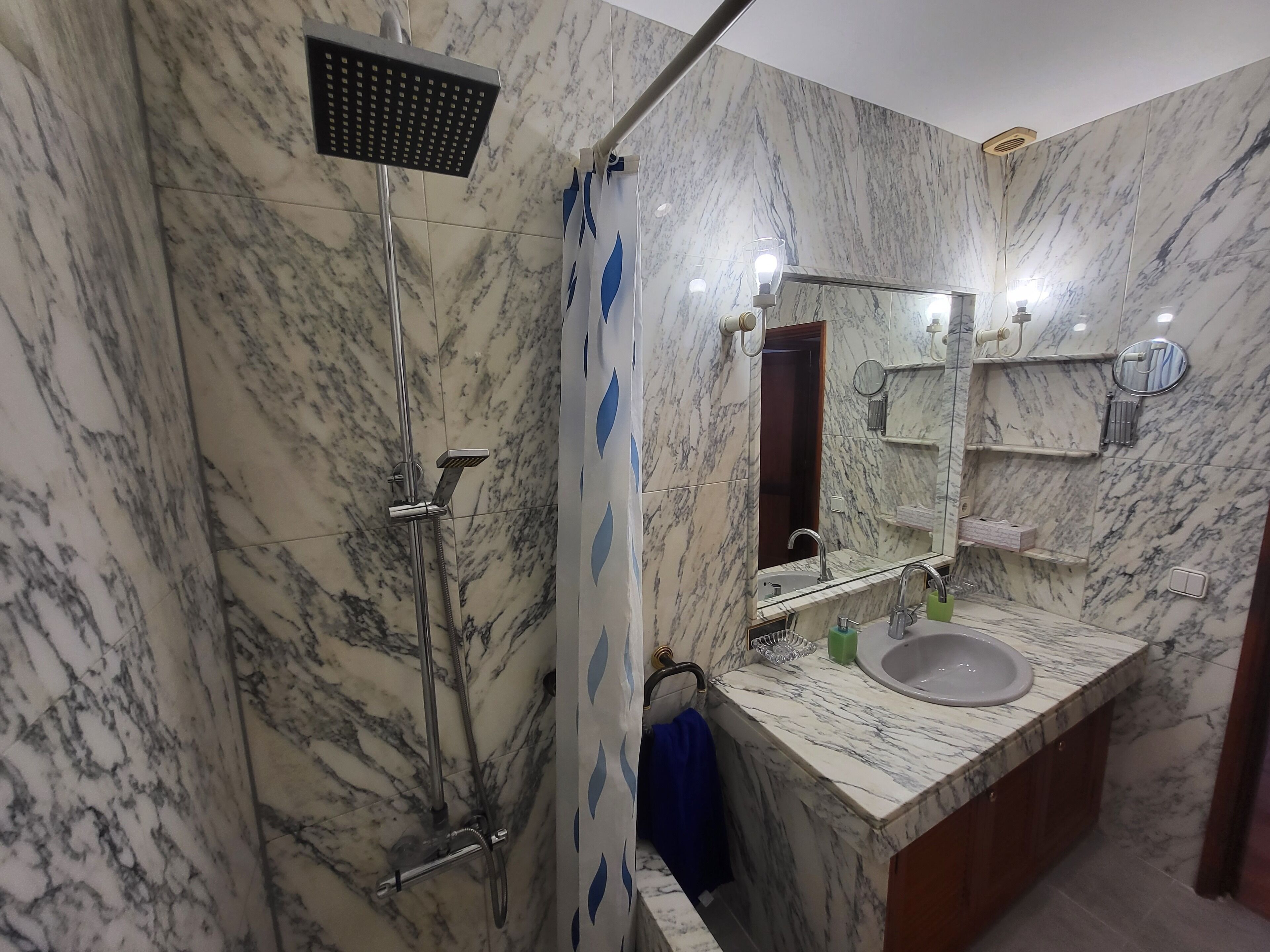 A bathroom with a shower, sink, and mirror.