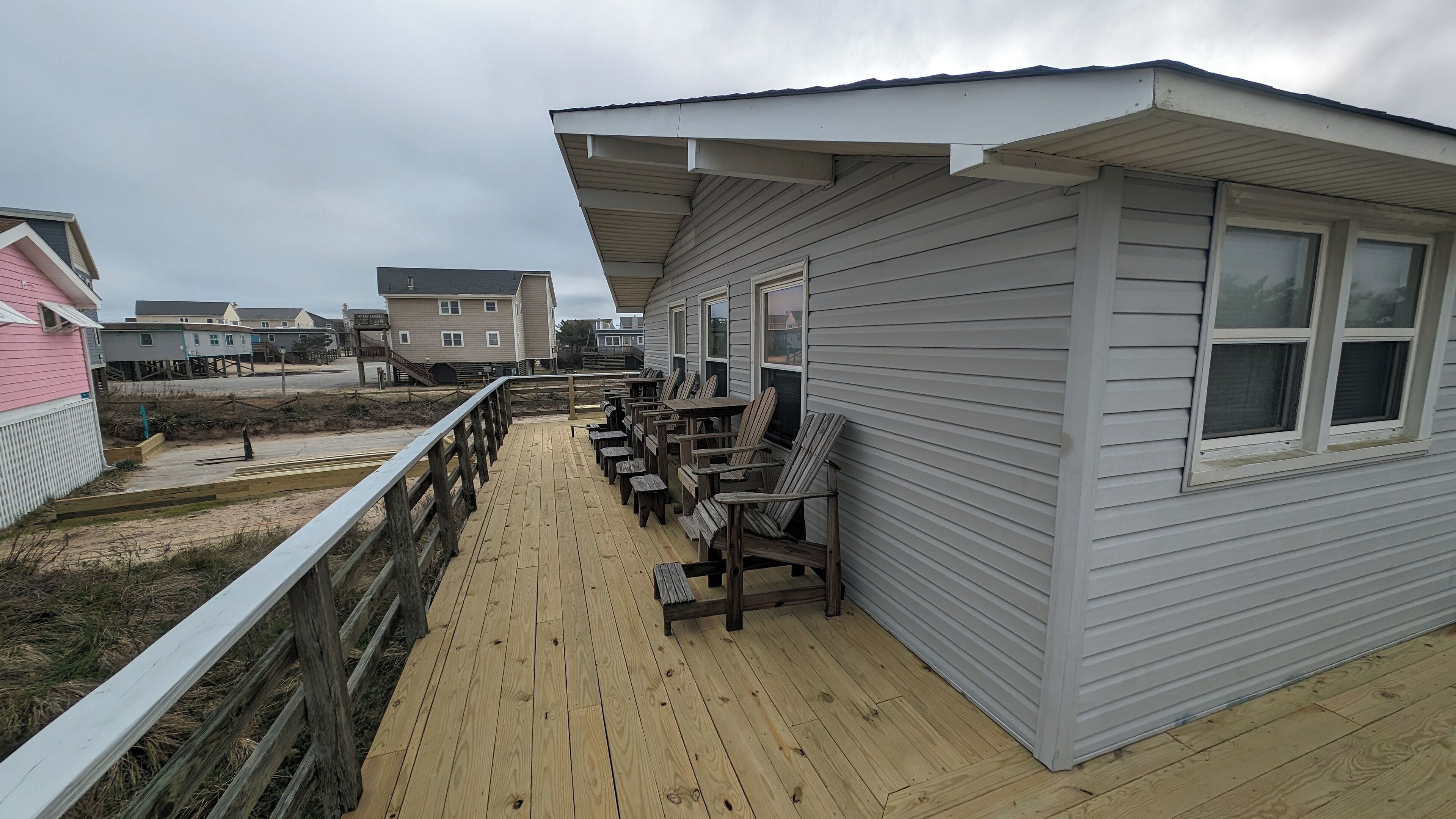 Eine Holzterrasse mit Sitzgelegenheiten und Blick auf den Strand.