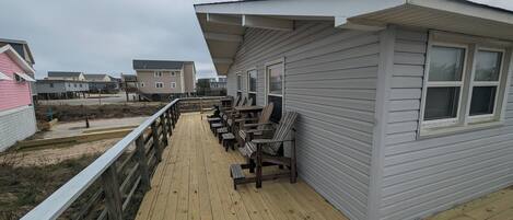 Eine Holzterrasse mit Sitzgelegenheiten und Blick auf den Strand.
