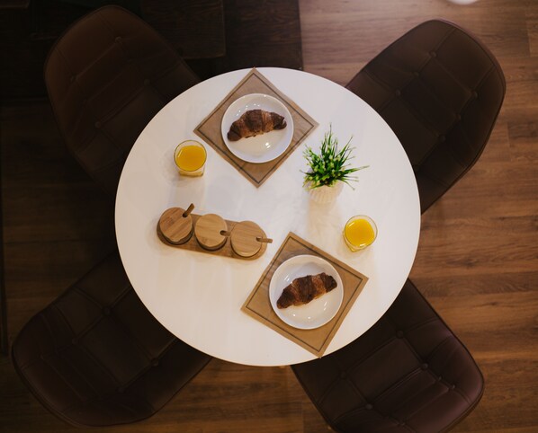 Une table ronde avec des assiettes de nourriture, un verre de jus de fruits et une petite plante.