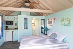 Una habitación con cama, ventilador de techo, kitchenette y baño.