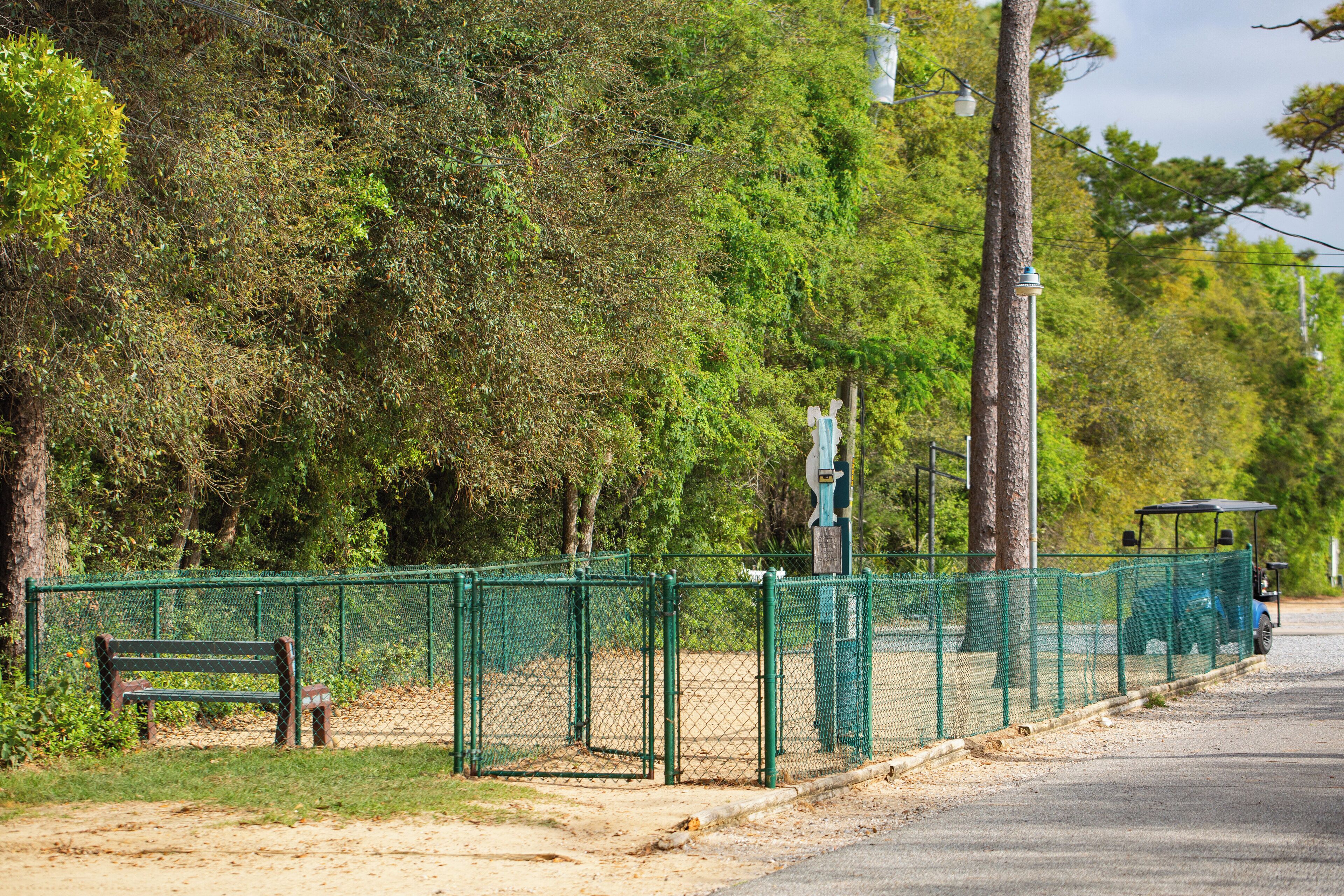 A fenced park area with a bench, a golf cart, and a street lamp.