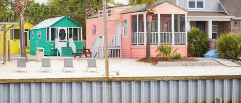 A beachfront property with a pool, a covered patio, and a house with a pink exterior.