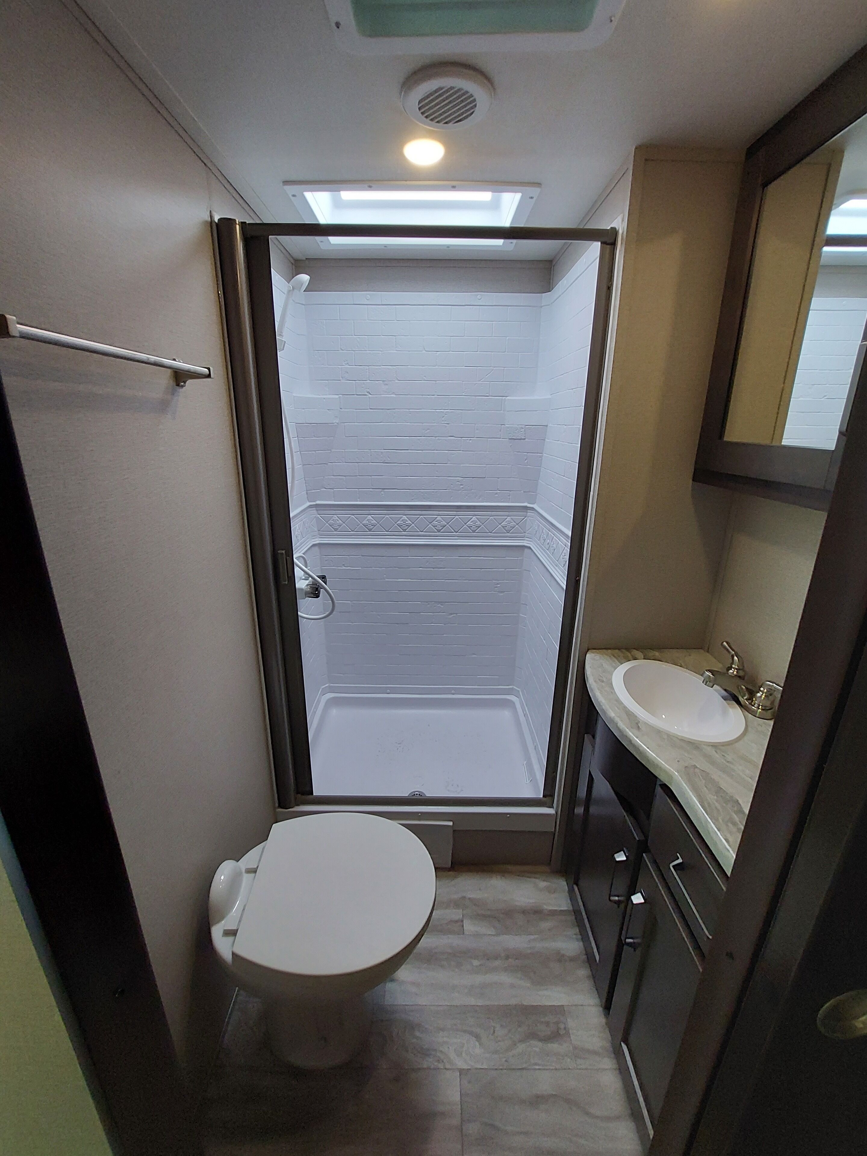 A compact bathroom with a toilet, sink, and shower stall.