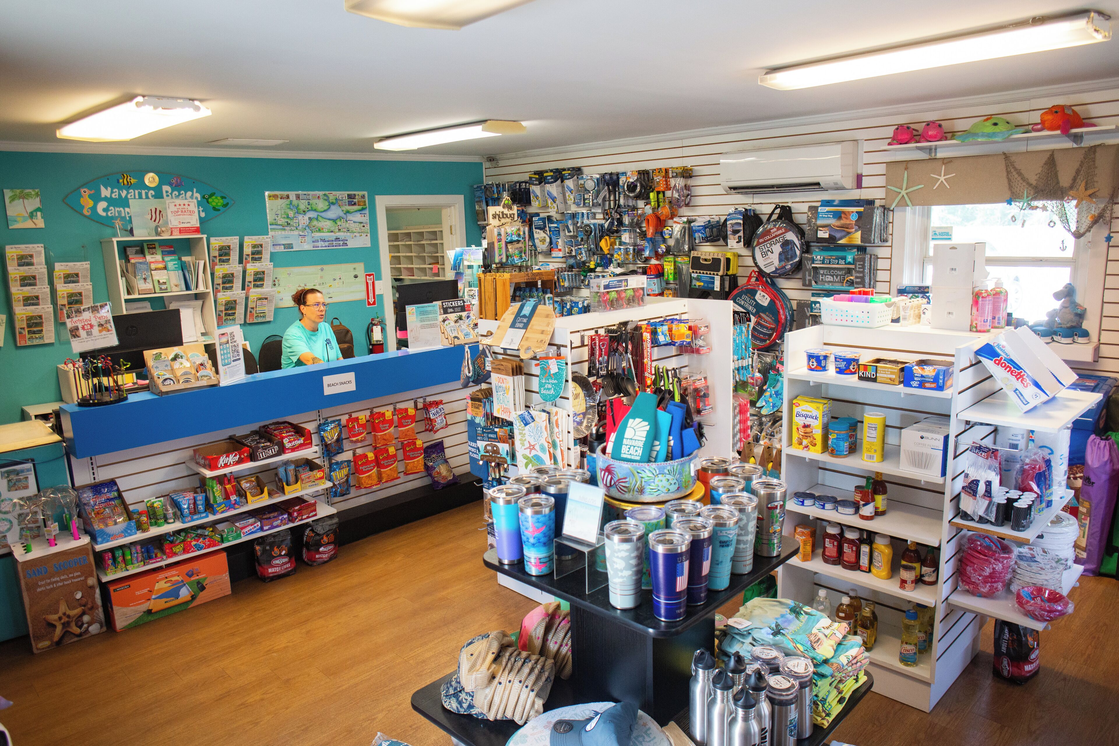 Un magasin dont les étagères sont remplies de divers articles, un comptoir derrière lequel se trouve un vendeur, et une enseigne accrochée au mur.