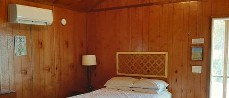 A wooden room with a bed, a desk, and a chair.