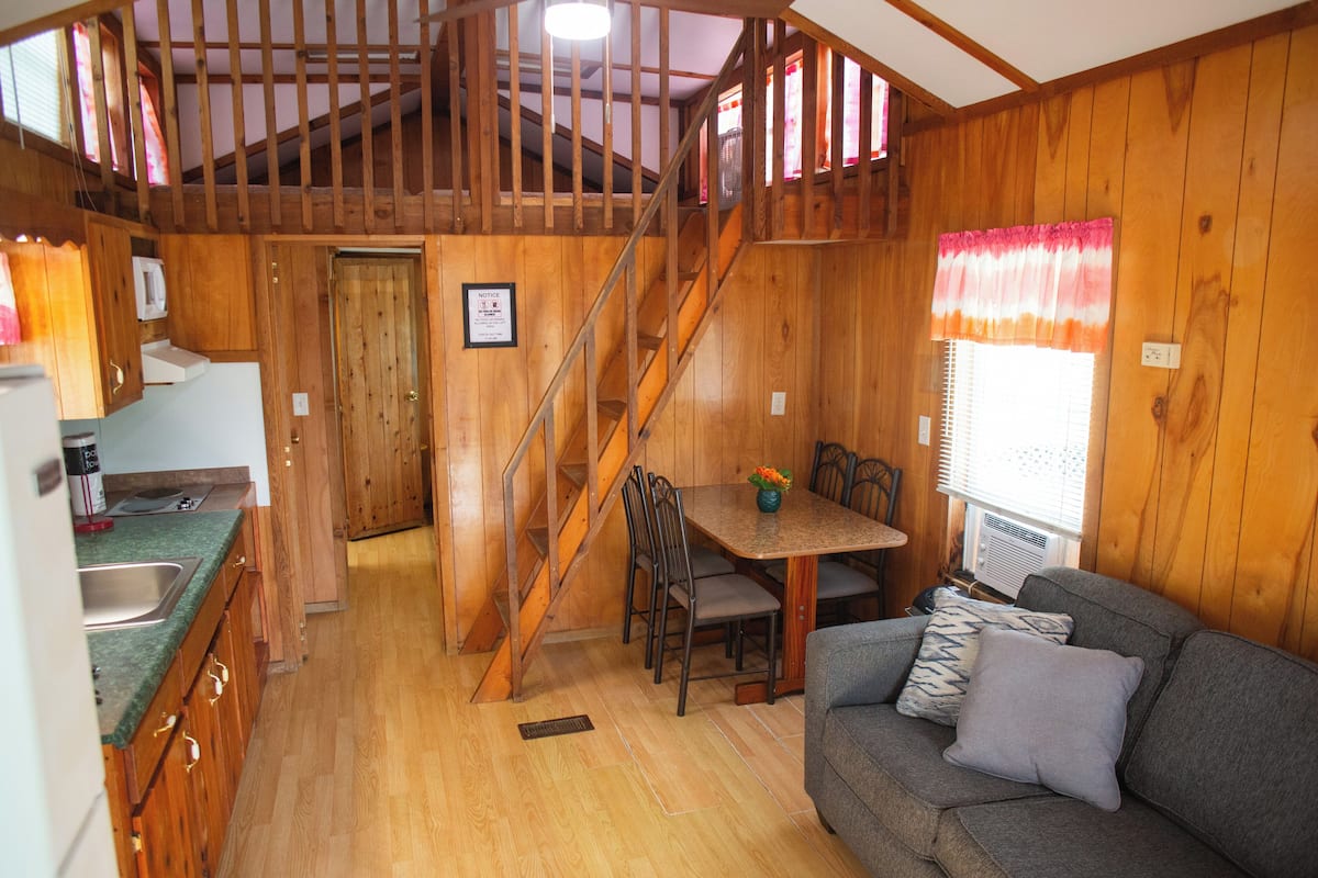 L’intérieur d’une cabane en bois comprend une cuisine, un coin repas et un salon.