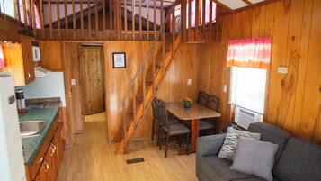L’intérieur d’une cabane en bois comprend une cuisine, un coin repas et un salon.