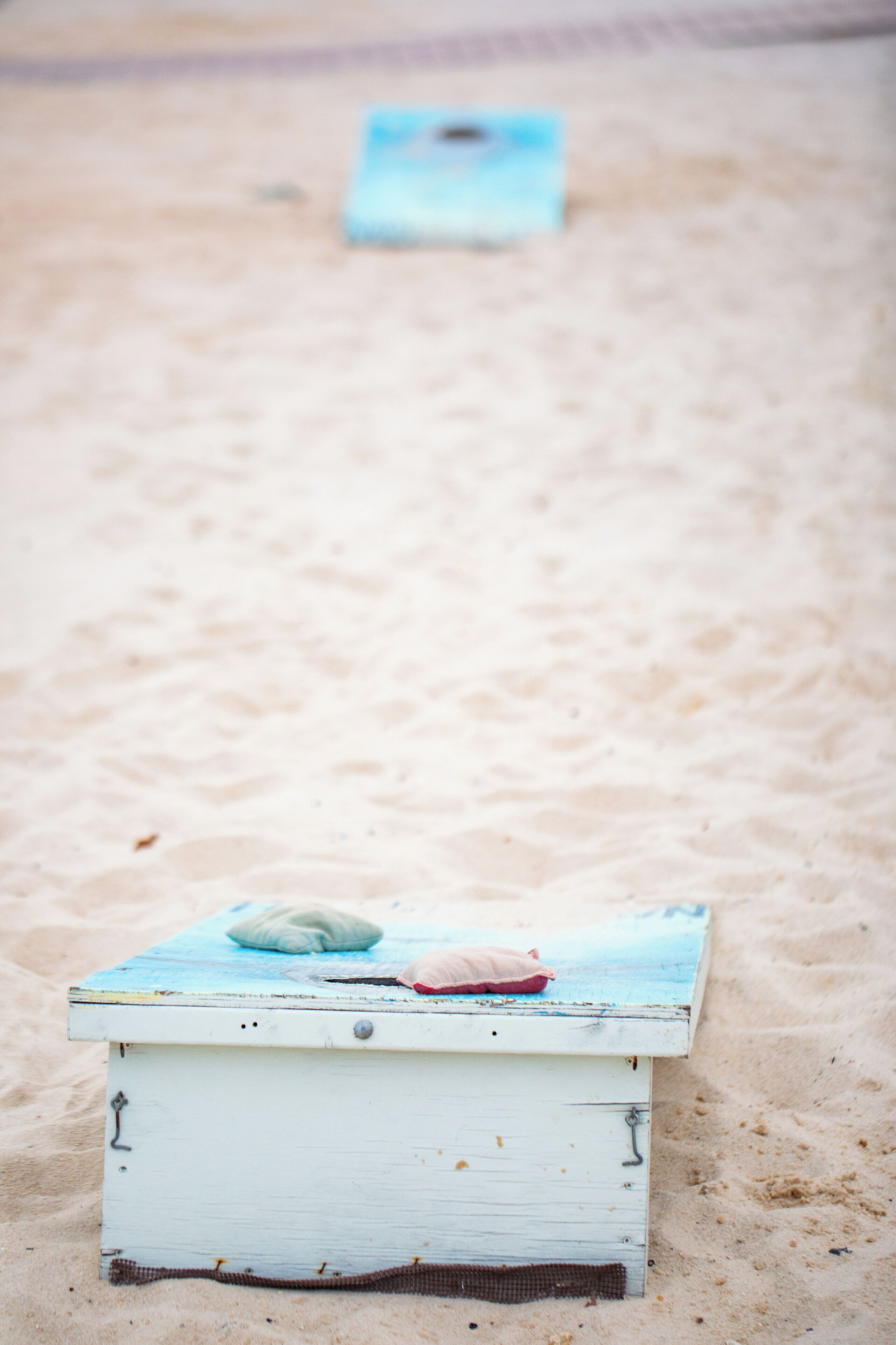 A beach scene with a white wooden structure with a blue top and a red object on it.