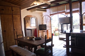 A wooden dining table with chairs, a television, and a kitchen area with a stove and microwave. - COLONIAL HOUSE IN NEW AND OLD SALTA (Salta)