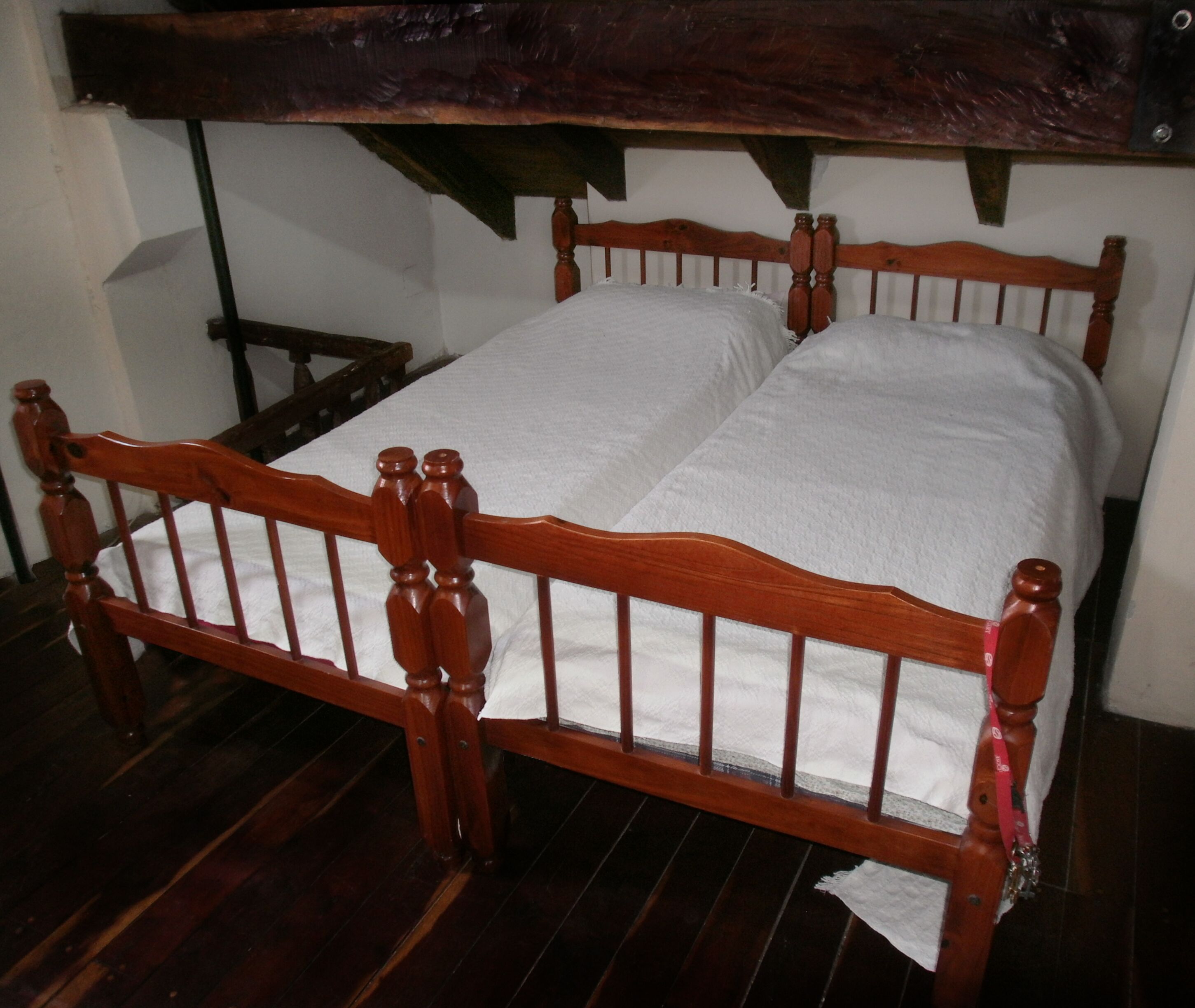 A wooden bed with a white mattress and a wooden headboard.