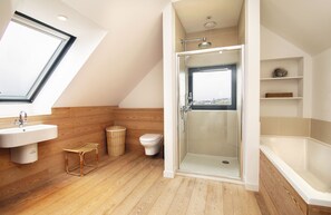 Un baño moderno con tragaluz, ducha con cerramiento de vidrio, bañera y retrete.
