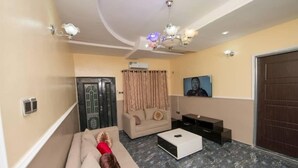Una sala de estar con sofá, mesa de centro, televisor y puerta.