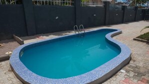 Una piscina rectangular con borde de azulejos, rodeada por un patio empedrado.